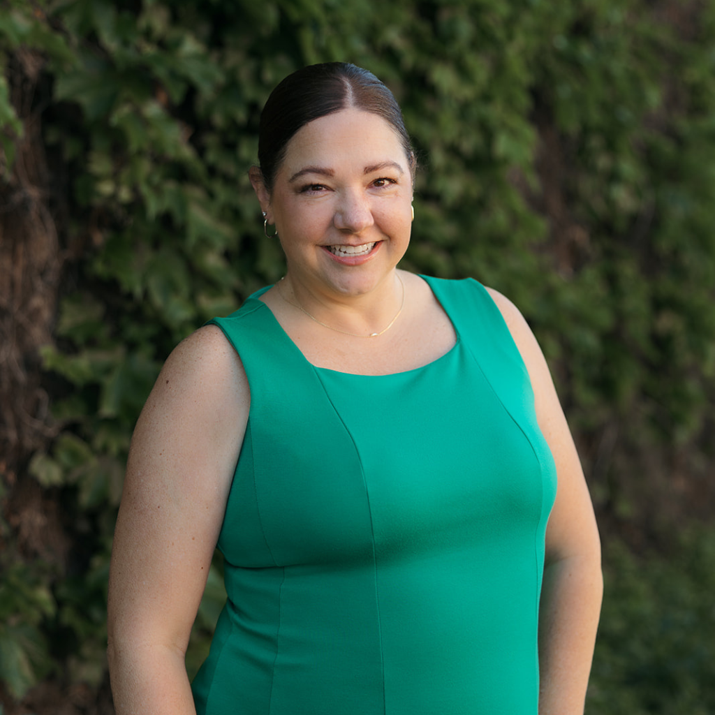 Woman wearing a green dress standing in front of a blurred natural background