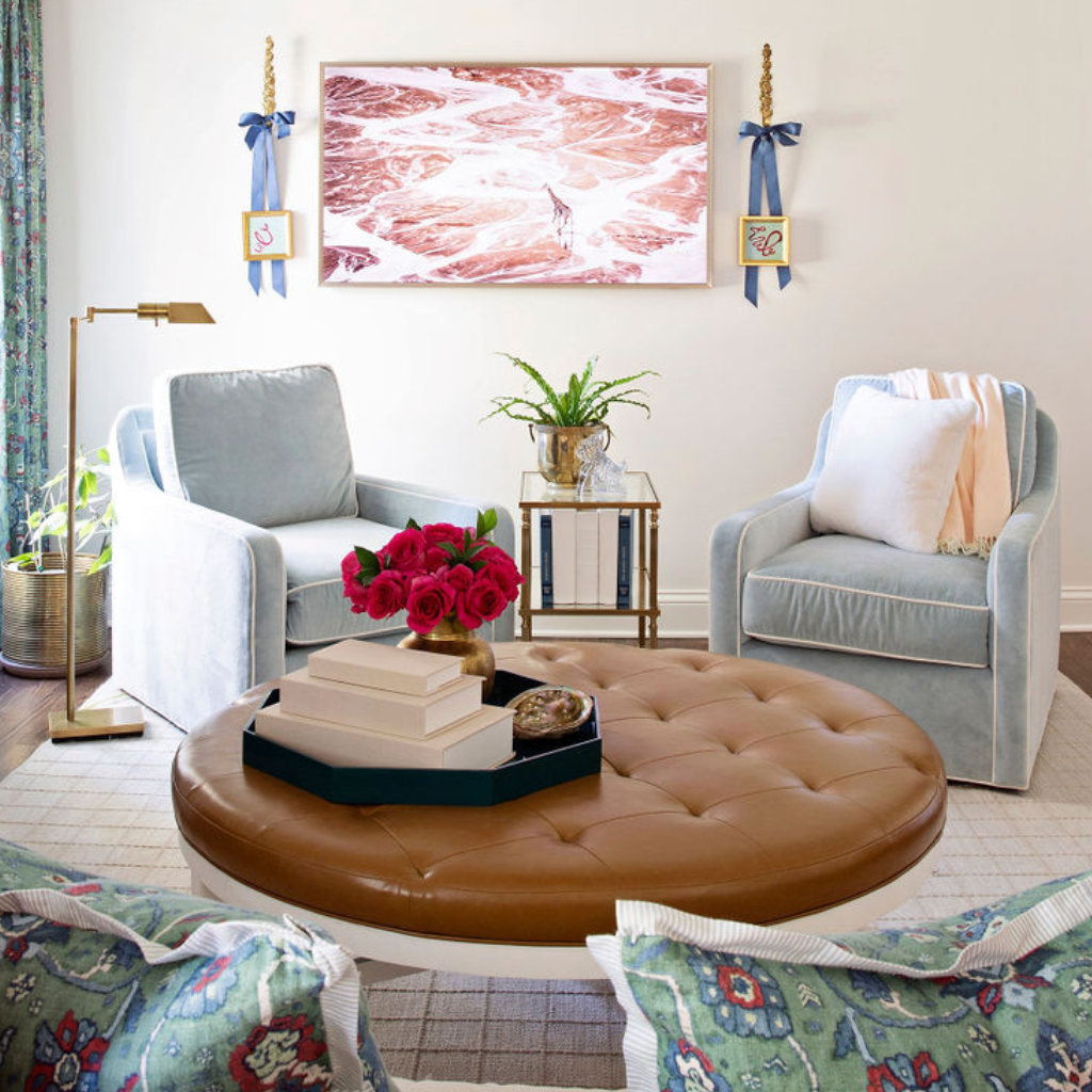 Living room with gray chairs, brown leather ottoman, and floral decor.